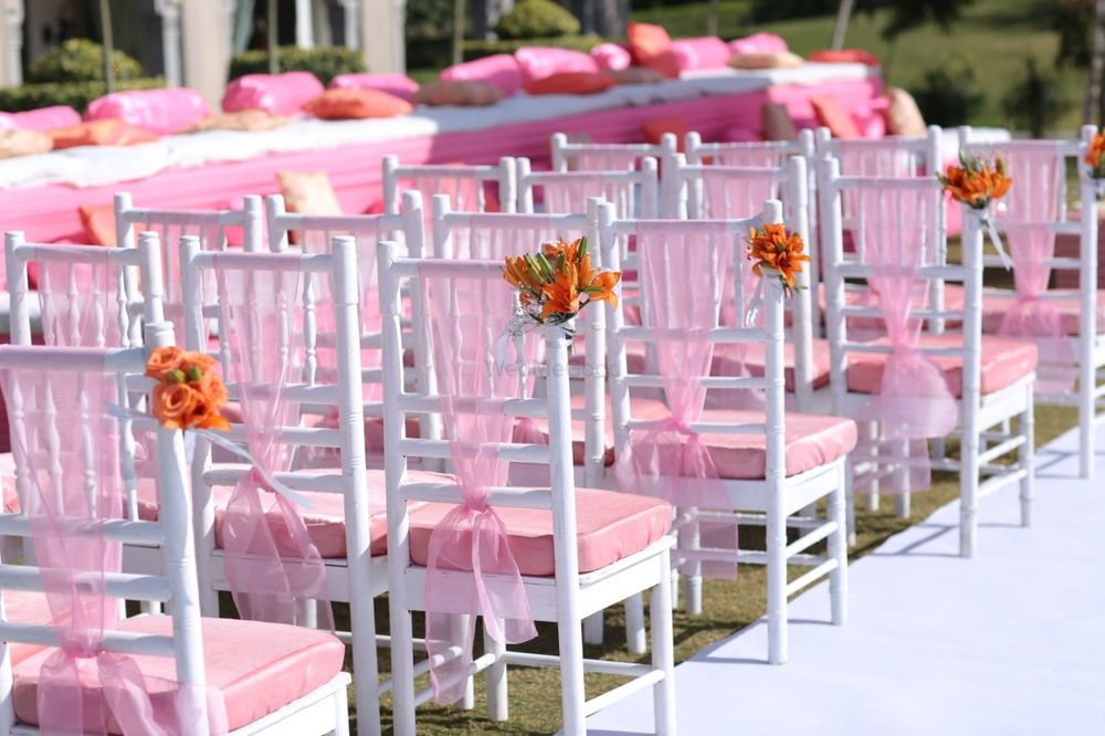 Photo of Chair backs decorated with pink ribbons and a bunch of flowers.