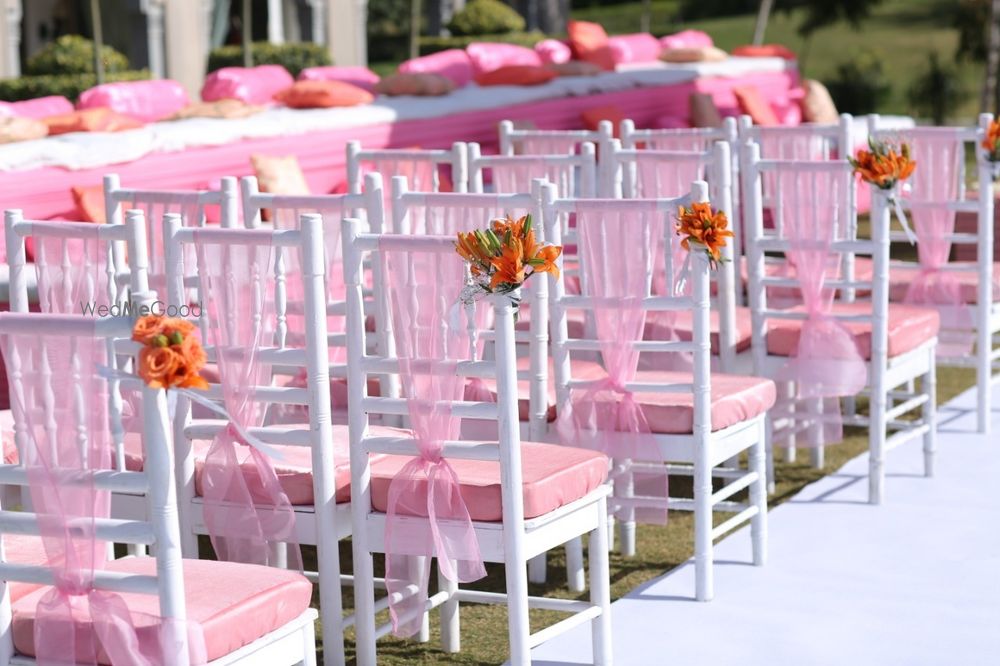 Photo of Chair backs decorated with pink ribbons and a bunch of flowers.