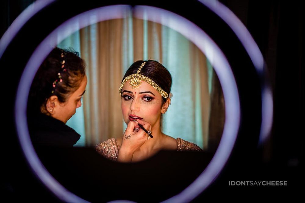 Photo of bride with mua putting makeup on her