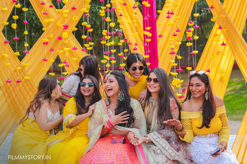 Photo of bride with her bridesmaids against yellow and pink backdrop