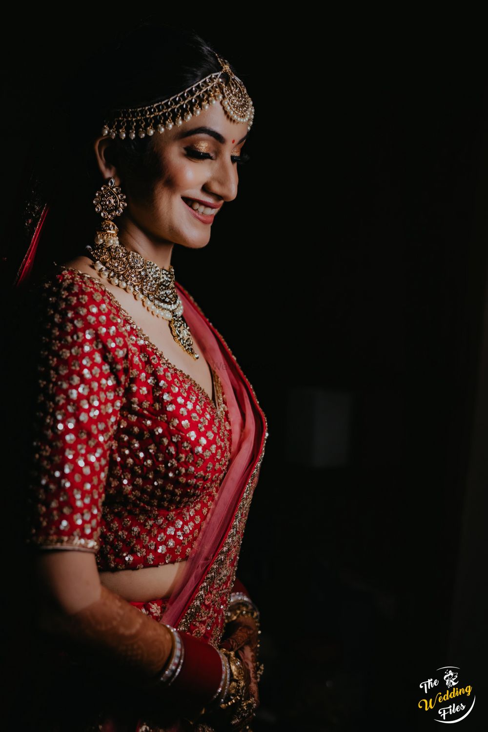 Photo of Candid shot of a smiling bride in a red lehenga.