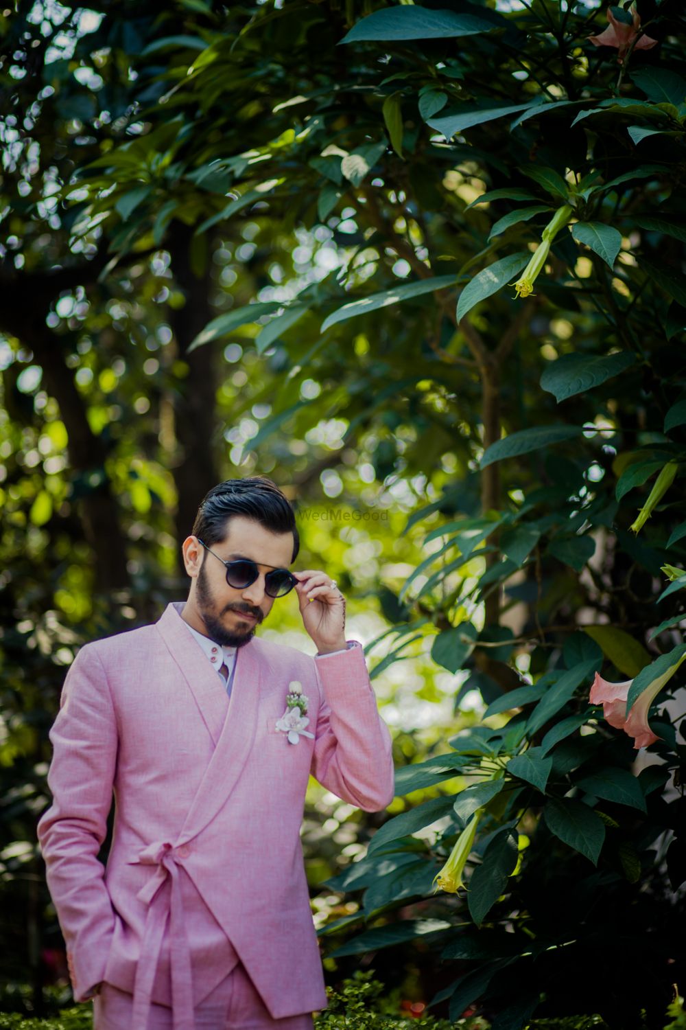 Photo of Groom dressed in a pink tuxedo with knotted details.