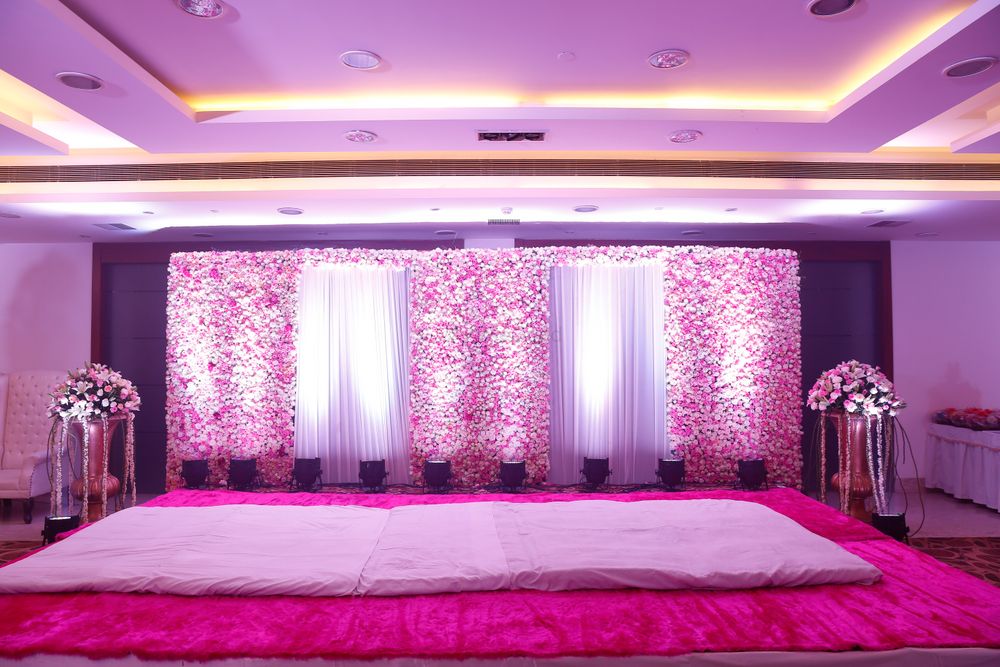Photo of stage backdrop with floral wall and white drapes