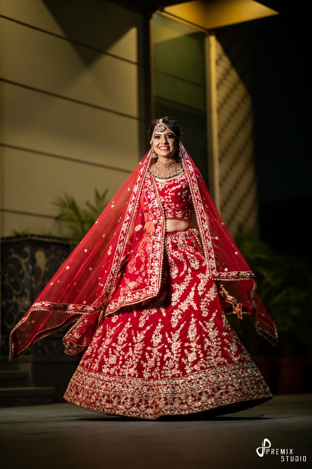 Photo of bride twirling in embroidered red lehenga