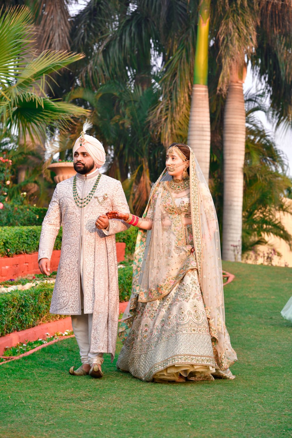 Photo of Candid shot of a royal Sikh couple color-coordinating in white.