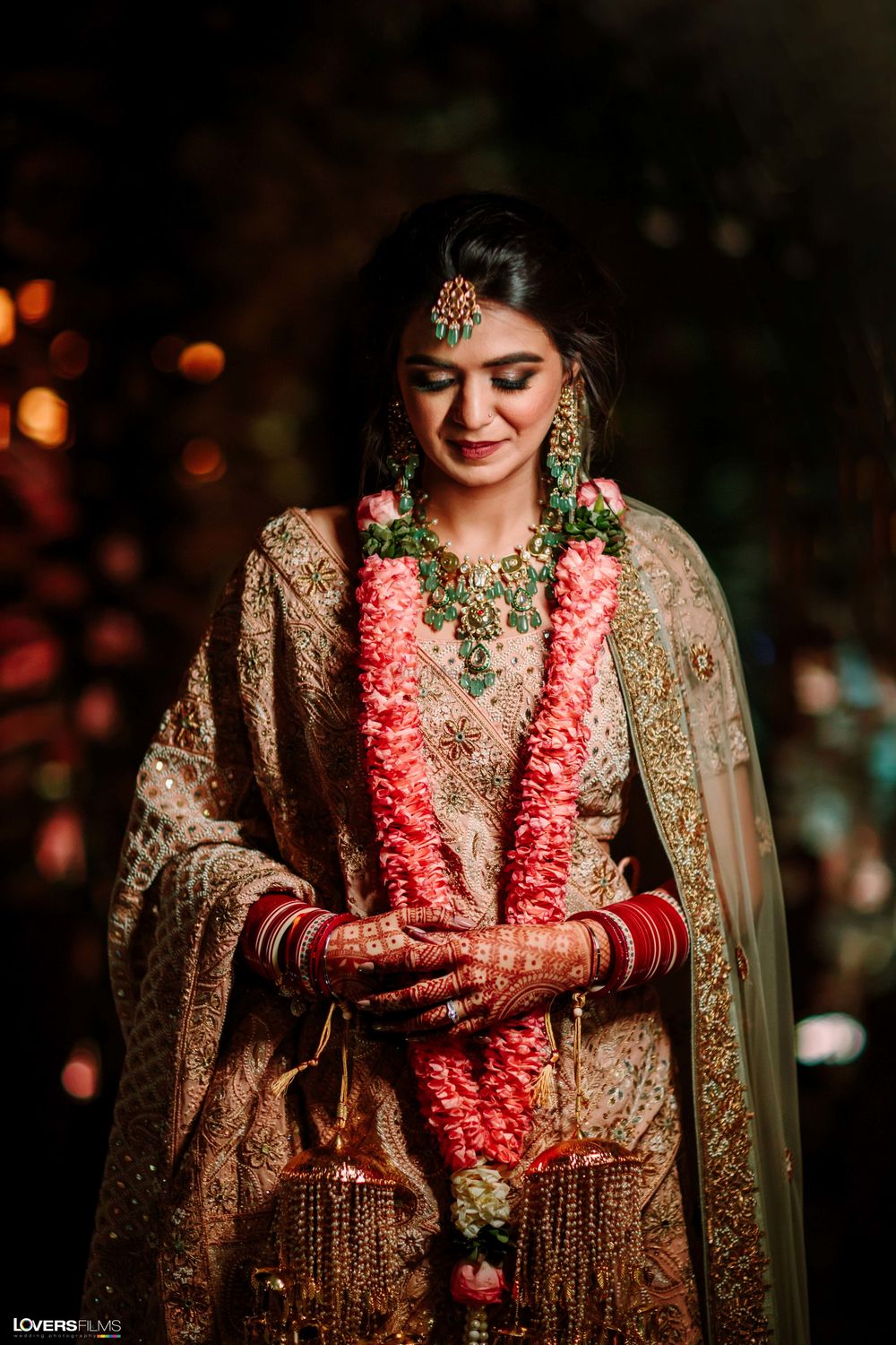 Photo of pastel bridal lehenga with unique green jewellery