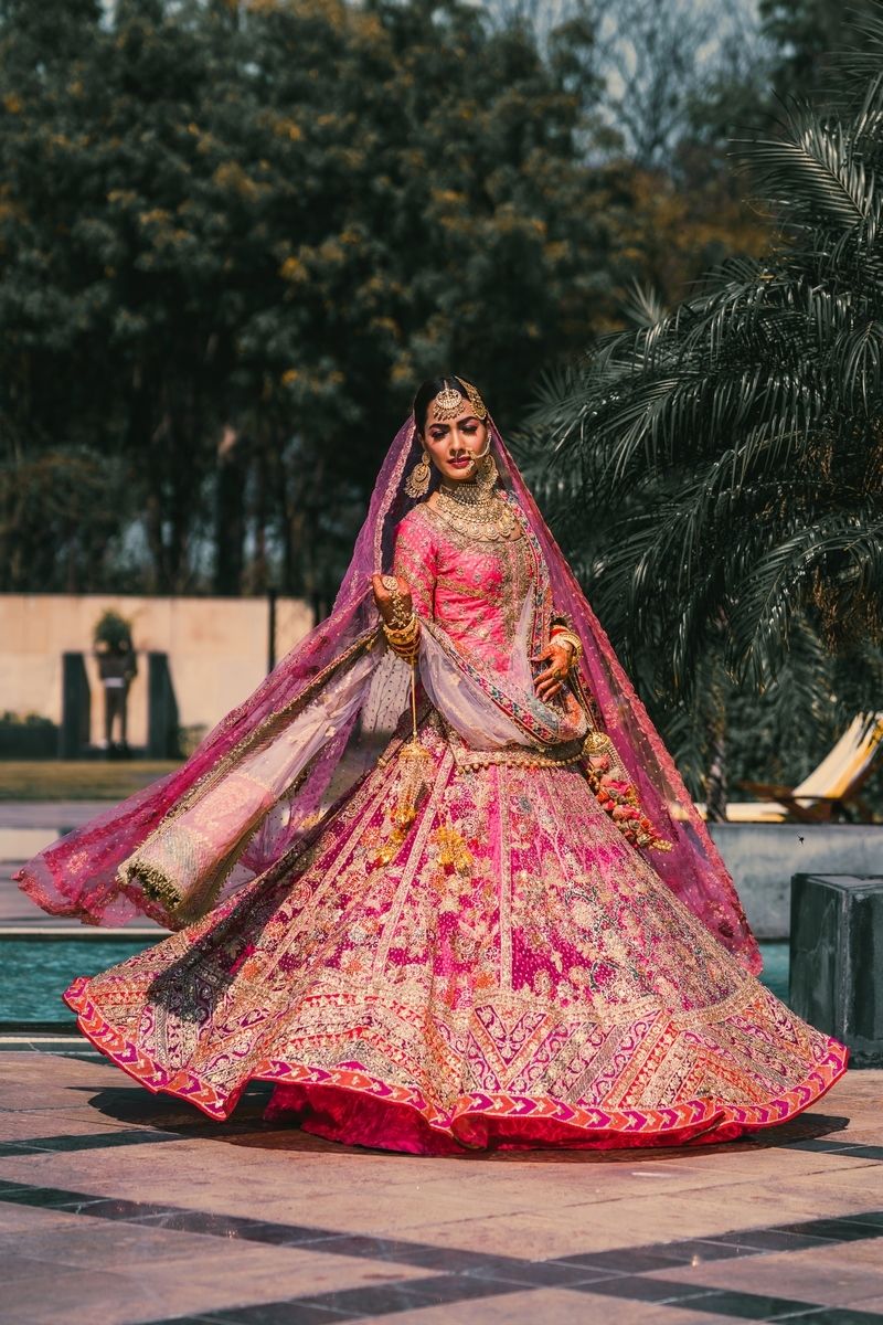 Photo of bride twirling in a hot pink lehenga