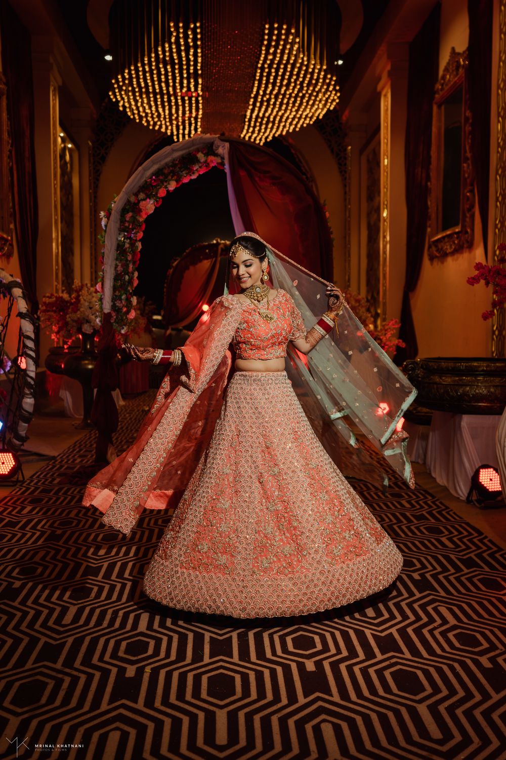 Photo of Twirling shot of a bride dressed in a coral lehenga.