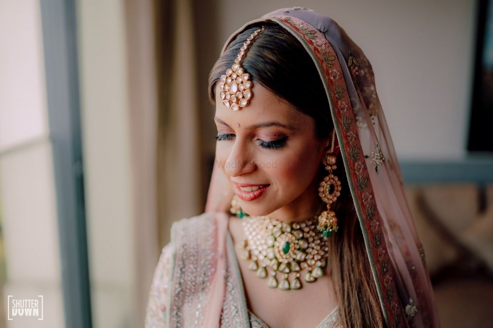 Photo of subtle bridal makeup with light pink lehenga with floral border