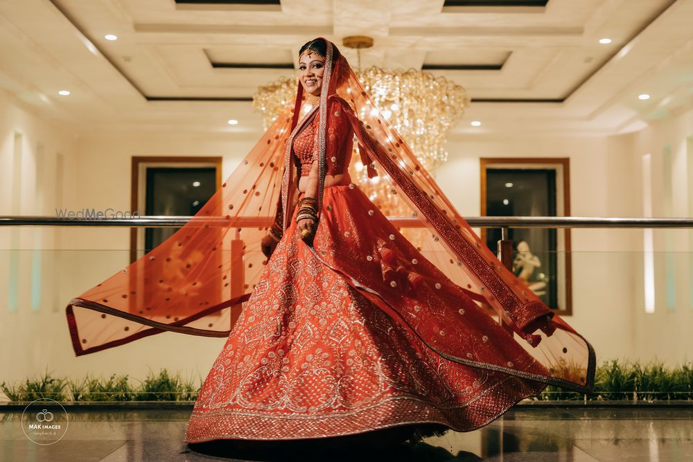 Photo of Twirling shot of a bride dressed in a red lehenga.