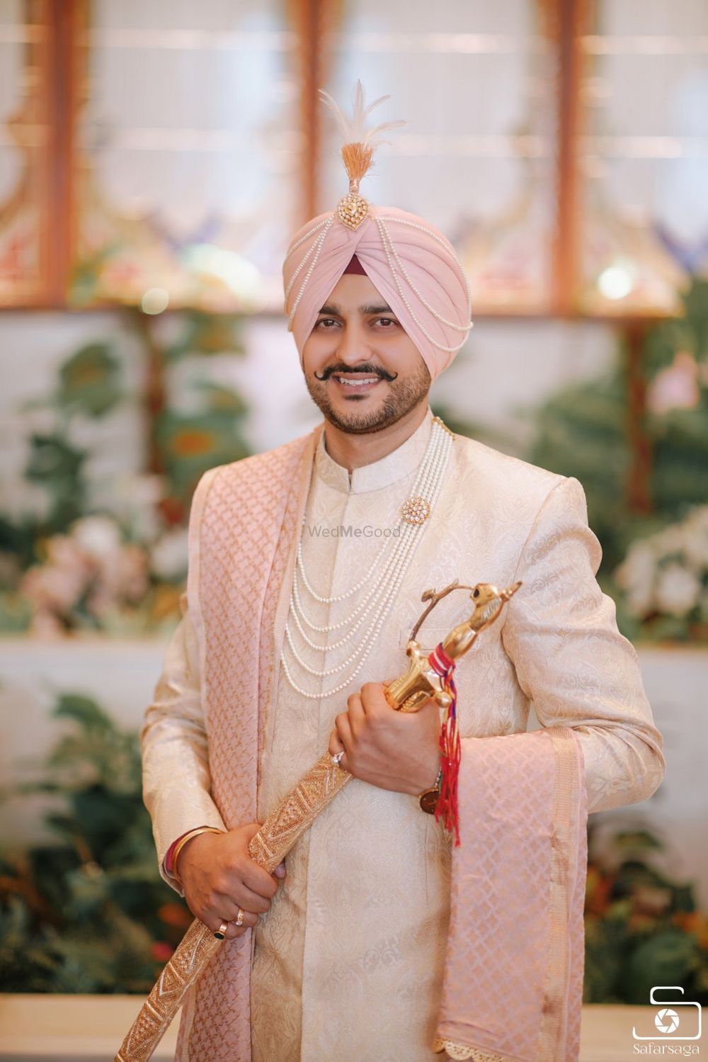 Photo of Groom wearing ivory sherwani with pink turban and stole.