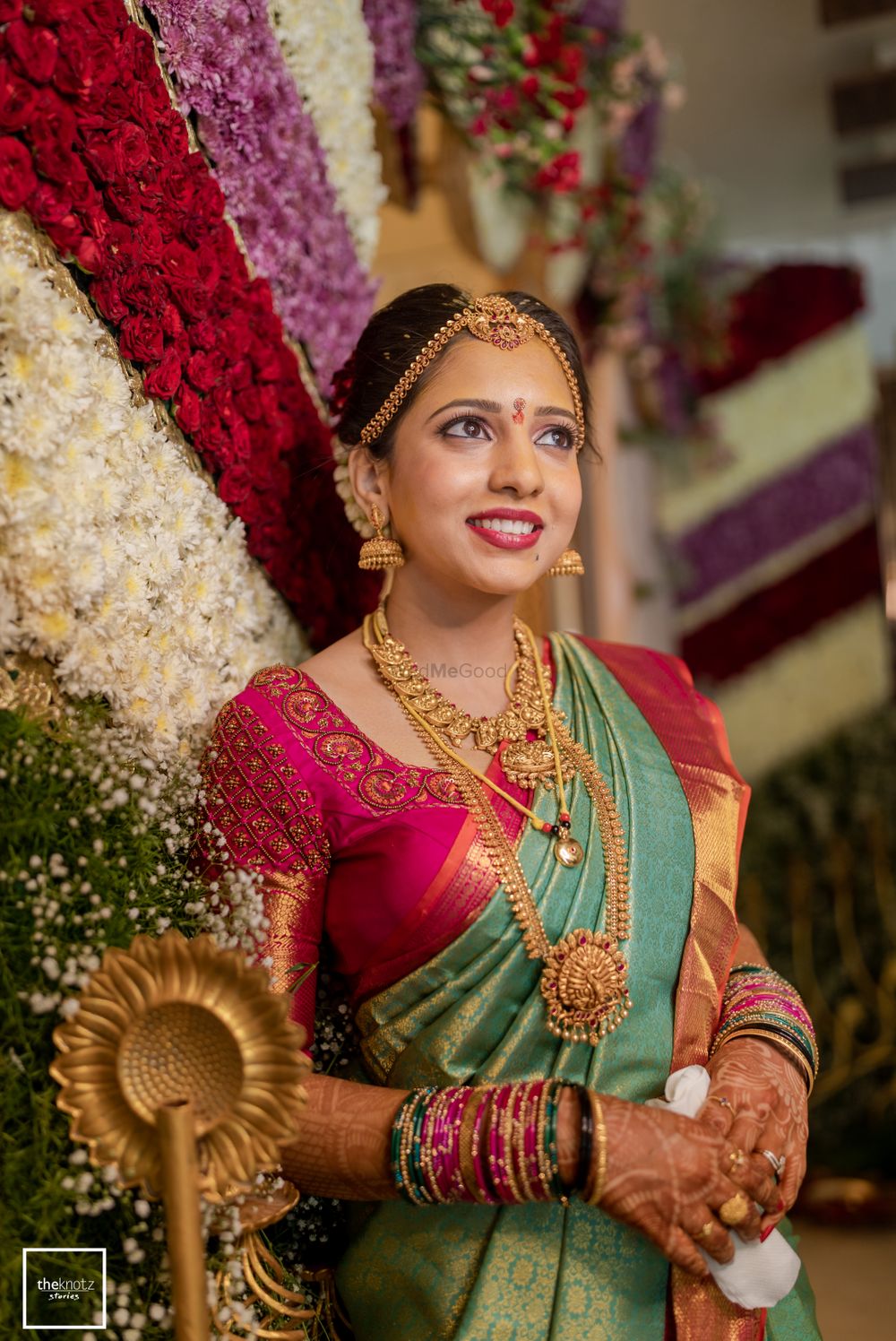 Photo of South Indian bride wearing a green and pink saree with temple jewellery.