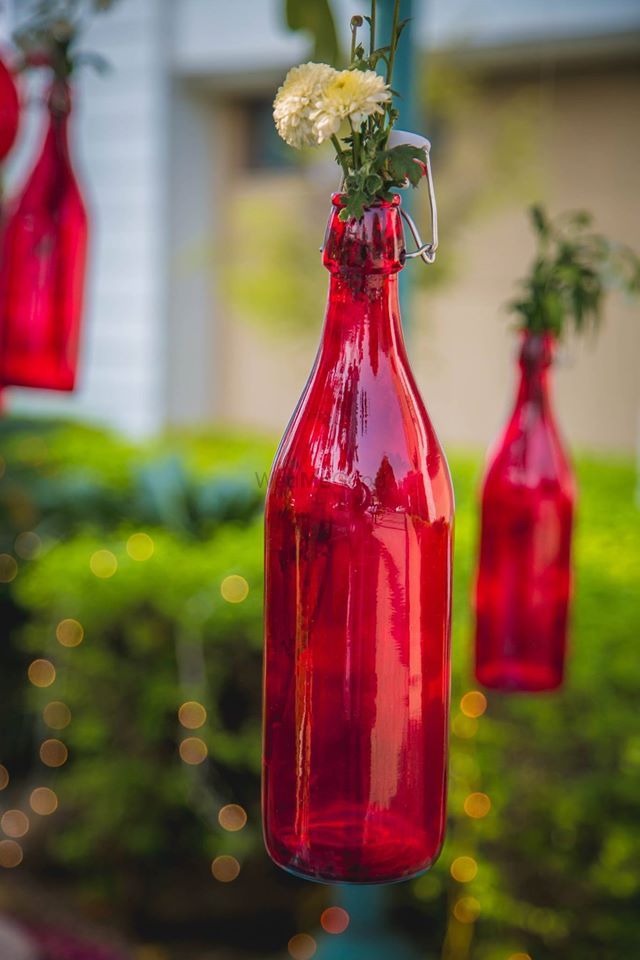 Photo of Suspended Coloured Glass Bottles with Flowers in Decor