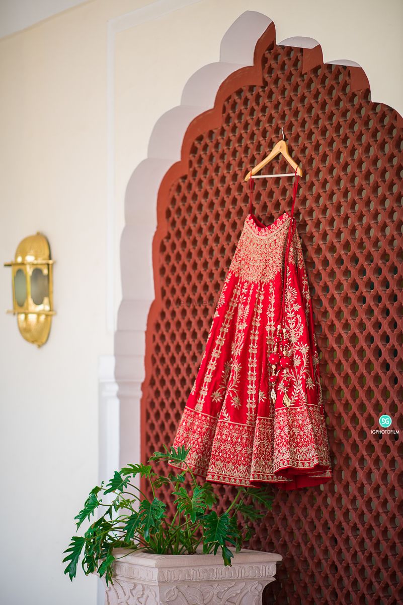 Photo of red bridal lehenga on a hanger in the room