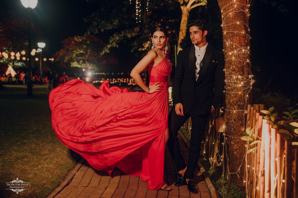 Photo of Bride and groom color-contrasting in red and black outfits.