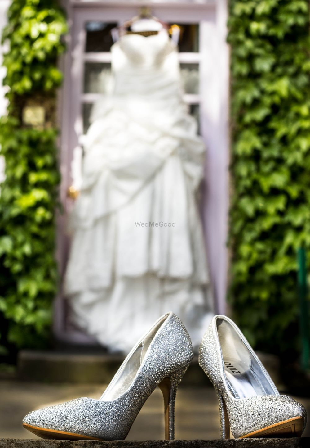Photo of Silver Wedding Shoes with Gown in Background