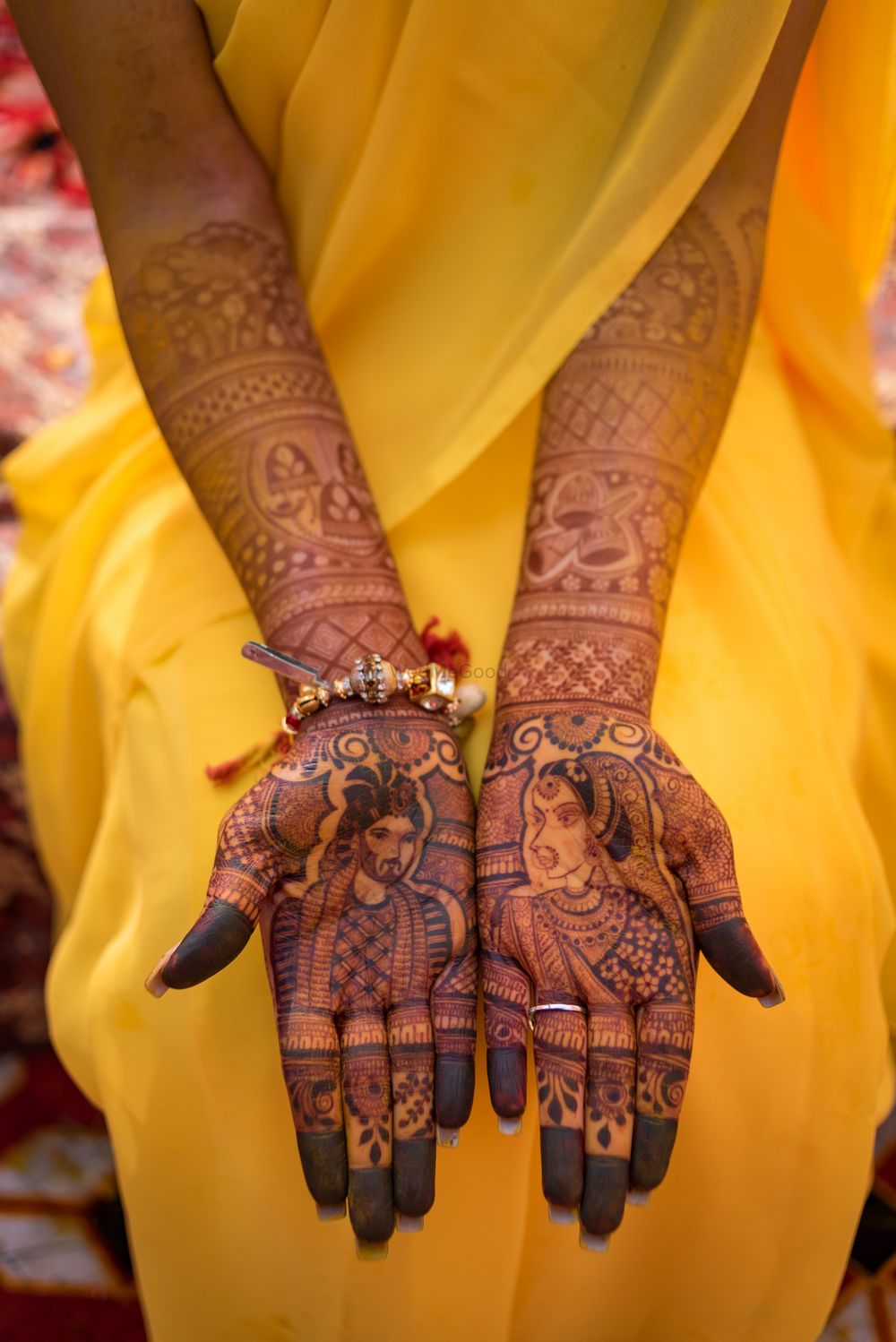 Photo of Full hand mehendi with bride and groom portraits.
