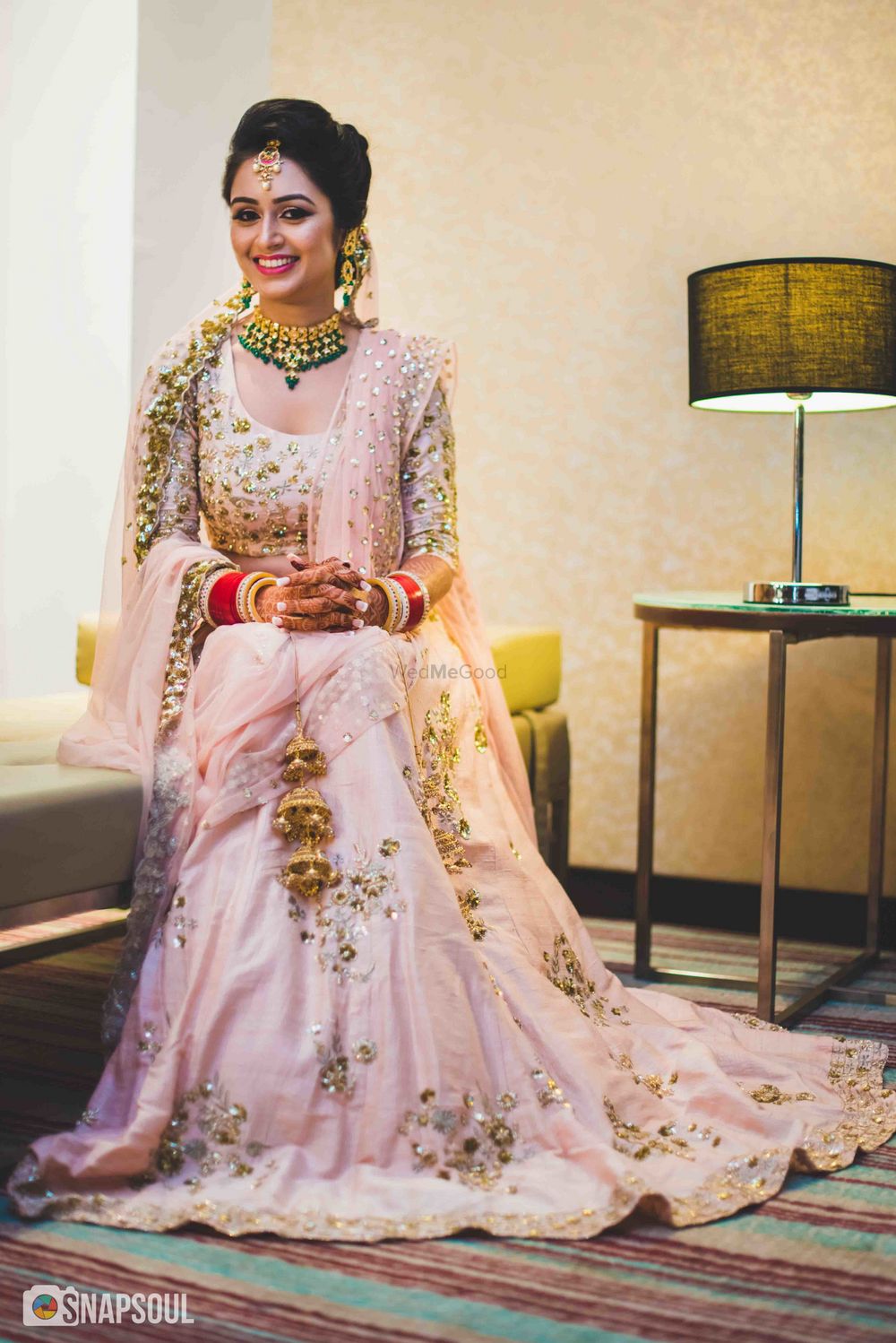 Photo of Pastel bridal lehenga in pink with green jewellery