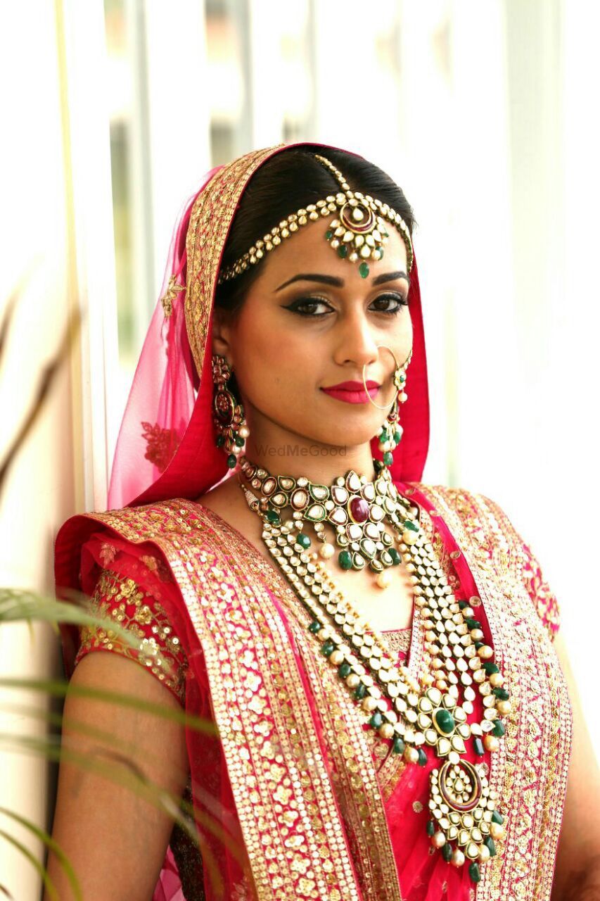 Photo of Bride in red with green polki jewellery