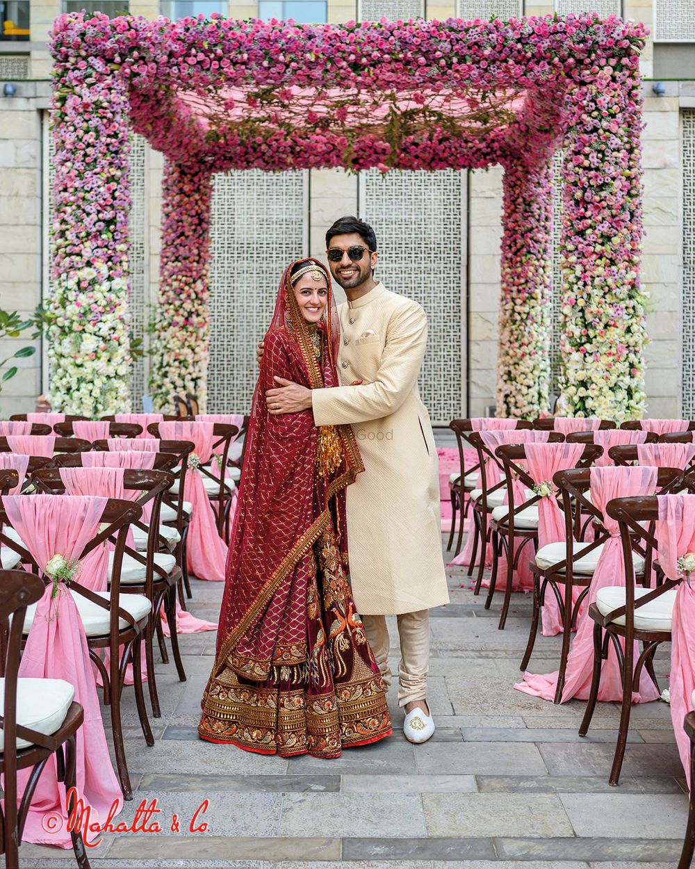 Photo of Bride and groom posing against the mandap.