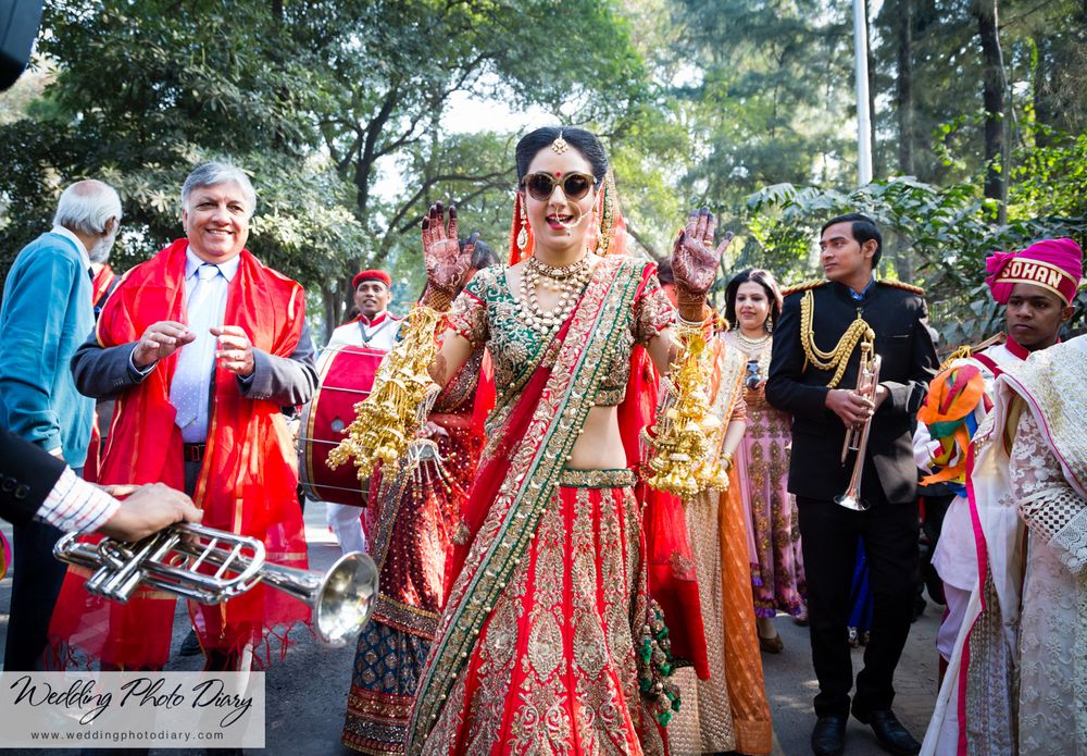 Photo of Bride in red and green lehenga wearing sunglasses