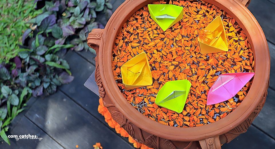Photo of Earthen pot with floating petals and paper boats