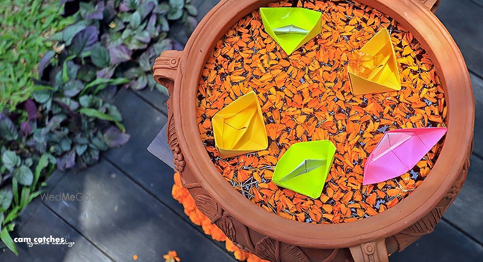 Photo of Earthen pot with floating petals and paper boats