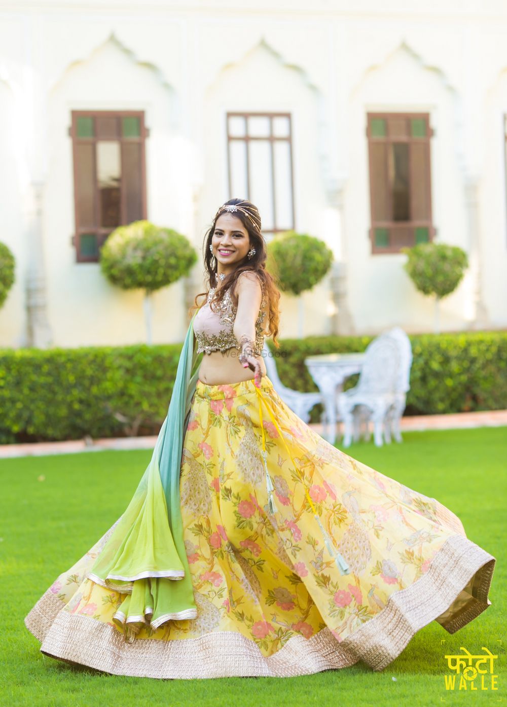 Photo of Bride twirling in yellow floral print lehenga