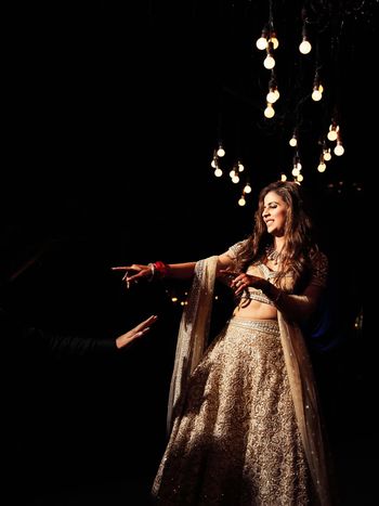 Photo of dancing bride shot in beige and gold lehenga on sangeet