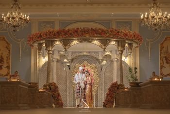 couple pose against grand south indian gold mandap