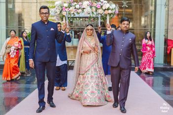 Photo of pastel pink sabyasachi bride entering under phoolon ka chadar