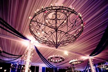 Photo of glamorous ceiling decor with wrought iron chandeliers and candles