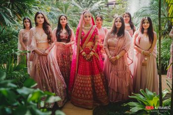 Photo of Bride in pink lehenga with coordinated bridesmaids in light pink outfits