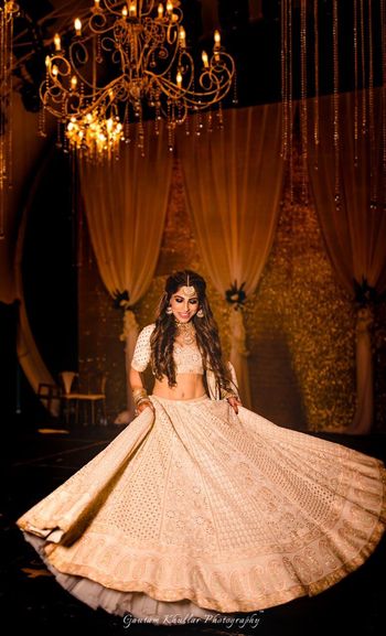 Photo of Twirling bride shot with Ivory and gold lehenga