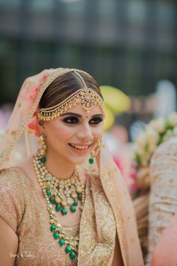 Pretty bridal portrait in peach lehenga and green jewellery 