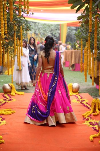 Photo of bright pink mehendi lehenga with purple dupatta and gold blouse