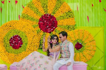 Photo of A bride and groom pose during their mehendi ceremony