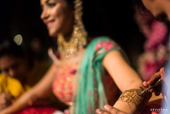 Photo of Bride getting mehendi put on arms