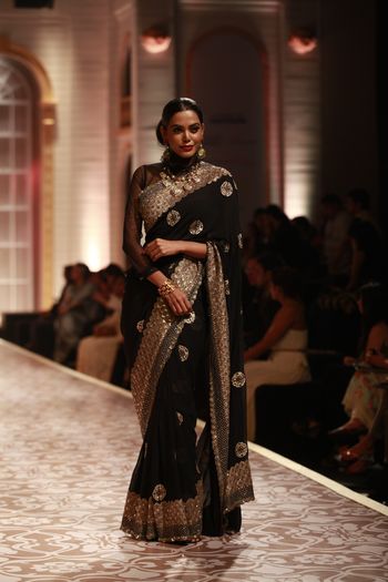 Photo of Elegant black saree with large border  and full sleeves high neck blouse