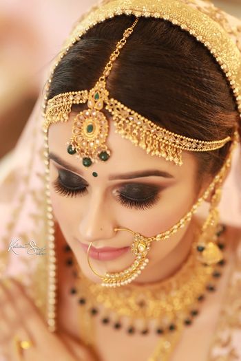Soft and subtle makeup with smoky eyes and gold jewellery. 