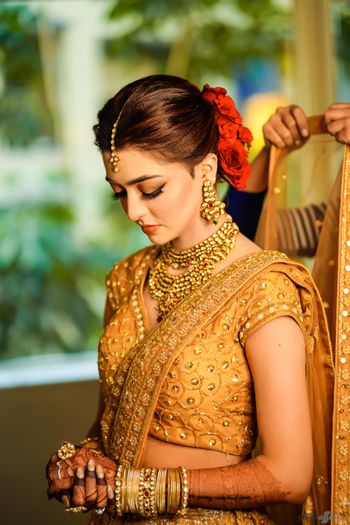 Photo of A bride in gold with red flowers in her hair
