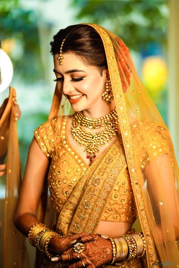 A shy bride in a golden lehenga on her wedding day 