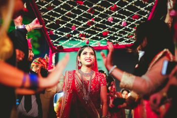 Glowing bride entering under phoolon ki chadar 