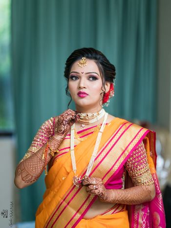 Marathi bride wearing an orange saree with a pink blouse.