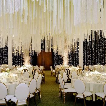Photo of White and gold table settings with fringes as ceiling decor.