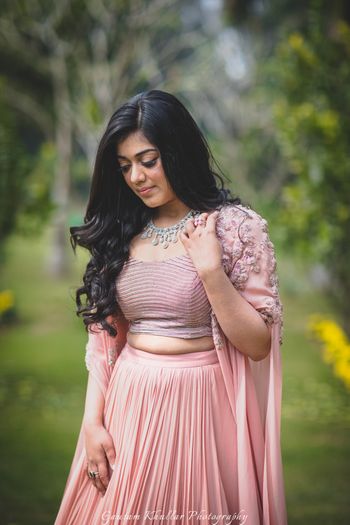Photo of Bride looking down in lehenga with cape sleeves