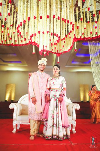 Photo of Coordinated bride and groom with floral strings on ceiling
