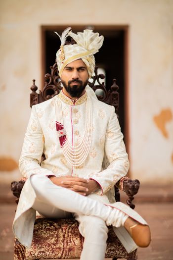 A groom in off white and gold sherwani with a matching safa
