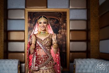 Photo of Bride wearing heavy jewellery with her maroon and gold lehenga