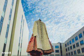 Photo of Lehenga and sherwani on hanger against the backdrop of the sky